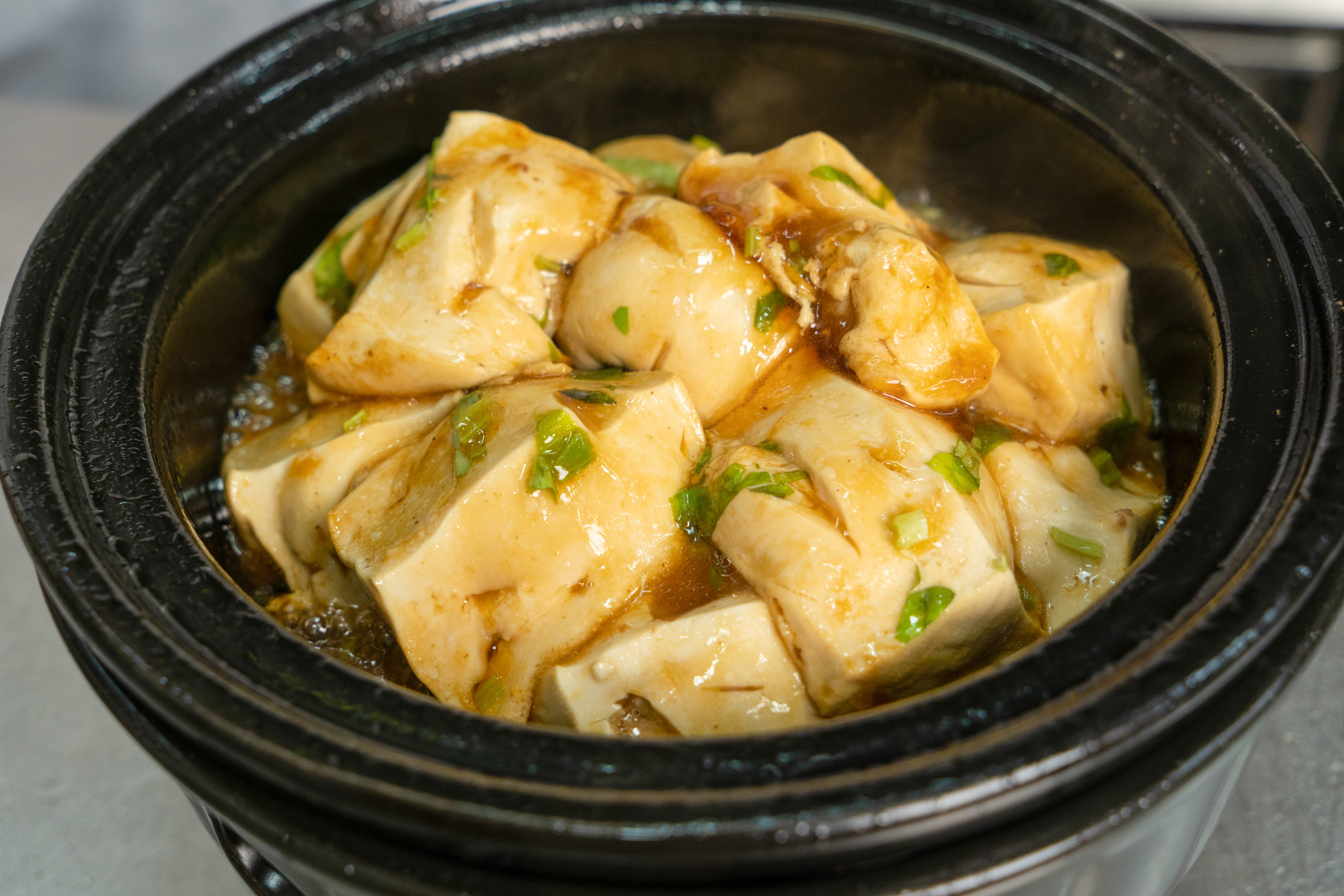 6、制作过程（曾成汉展示）：把“壳”（煎）好的酿豆腐放入“泥煲”用文火慢炖后，撒入葱花出锅。（拍摄时间：2021年11月20日， 拍摄地点：五华县金五福饭店，拍摄者： 古民辉）.jpg
